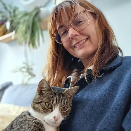 Wendy, professional cat sitter in Didsbury and South Manchester, cuddling a tabby and white cat